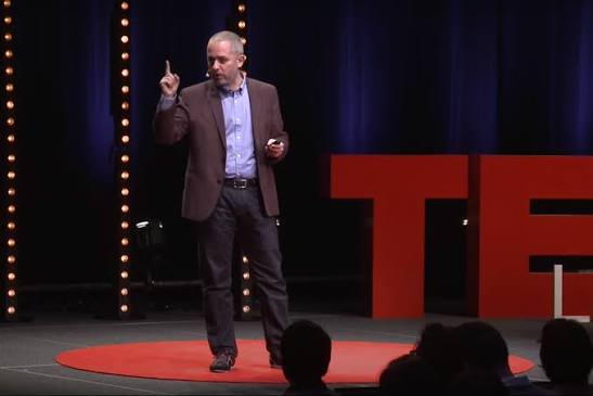 Professor John Antonakis giving his TED talk on leadership, standing on stage.